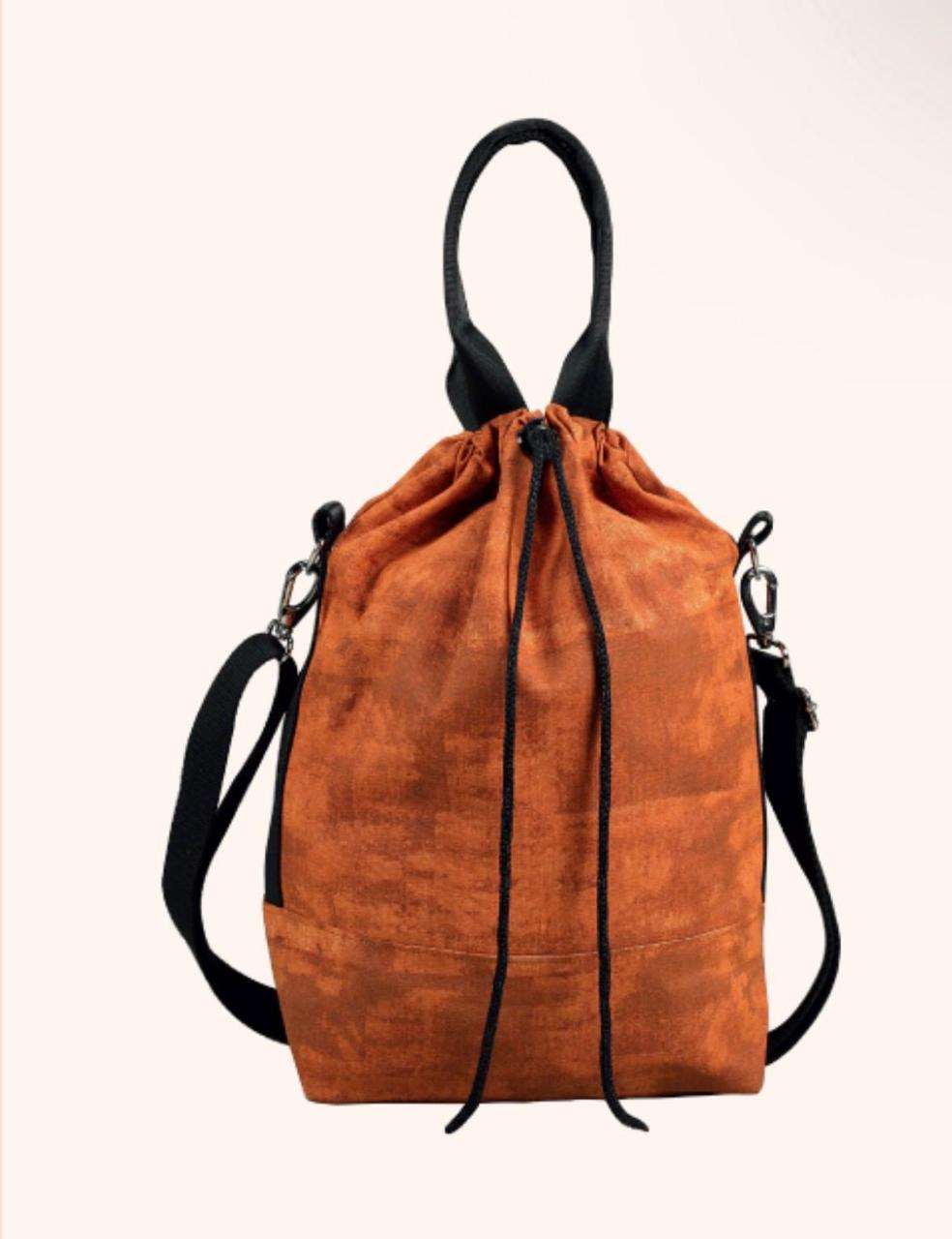 An orange-brown textured drawstring backpack with black handles and a black shoulder strap, shown against a plain off-white background.