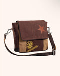 A brown and tan patchwork canvas messenger bag with a brown leather star patch on the flap and a circular gold-toned emblem on the front pocket, shown against a plain off-white background.