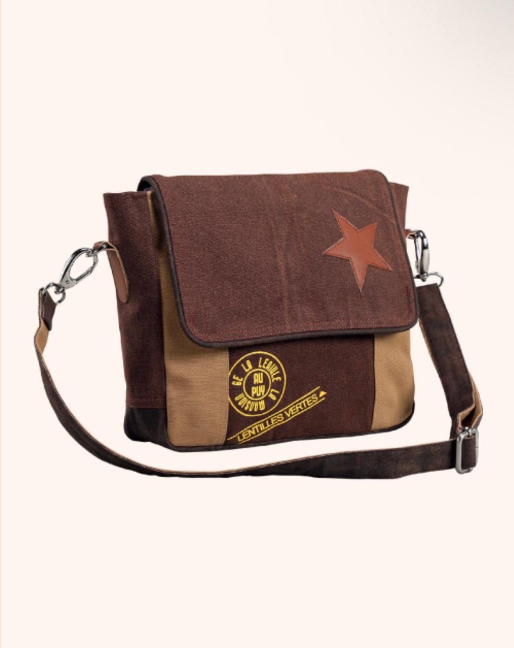 A brown and tan patchwork canvas messenger bag with a brown leather star patch on the flap and a circular gold-toned emblem on the front pocket, shown against a plain off-white background.