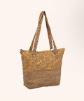 A cork tote bag with a yellow honeycomb pattern on the upper half and a solid cork textured lower half, featuring dual shoulder straps, shown against a light beige background.