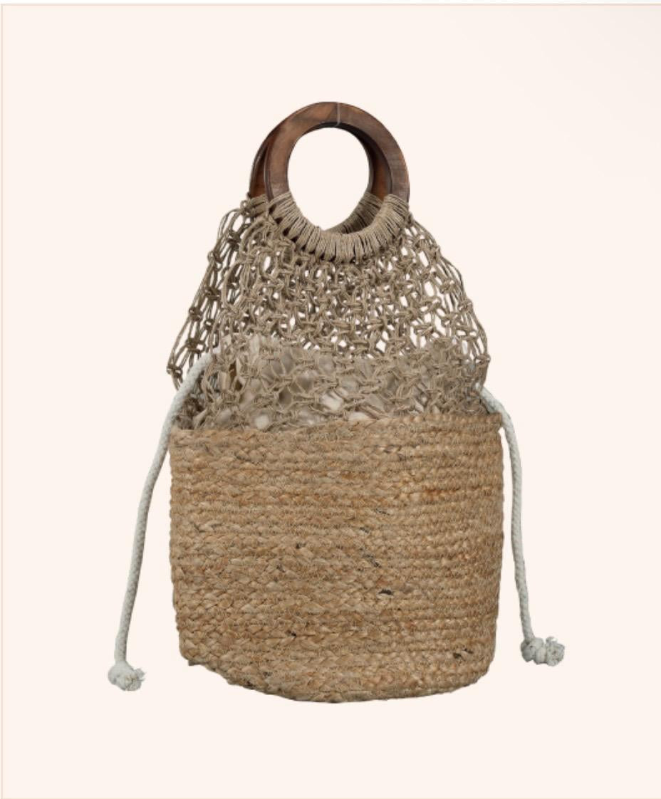 A natural woven straw tote bag with a circular wooden handle, a knotted crochet-style top section, and drawstring ties, shown on a plain light beige background.